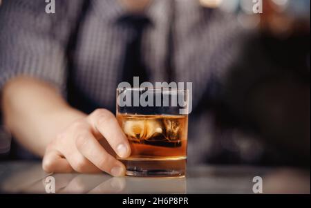 Barman hält Glas Whisky mit Eis für männliche Besucher aus. Konzeptruhe in der Bar. Stockfoto