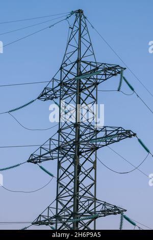 Die Metallstützen einer Hochspannungsleitung gegen einen blauen Himmel. Das Konzept der Energiekrise in Asien und Europa Stockfoto