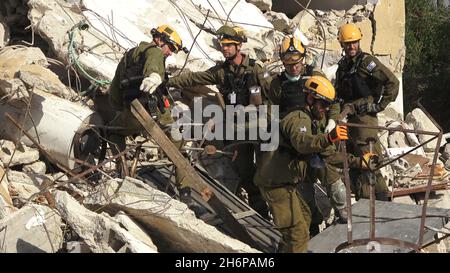 Israelische Soldaten der Rettungseinheit des Kommandos der Heimatfront gehen durch die Trümmer eines eingestürzten Gebäudes, während sie am 16. November 2021 in Tel Aviv, Israel, an einer Such- und Rettungsübung an einem großen Abrissplatz teilnehmen. Die Home Front-Übung simulierte Such- und Rettungsaktionen, die sich auf Szenarien vorbereiten, die Gebäude zerstören und Bürger aufgrund eines schweren Erdbebens oder massiver Raketeneinschläge einfangen könnten. Stockfoto