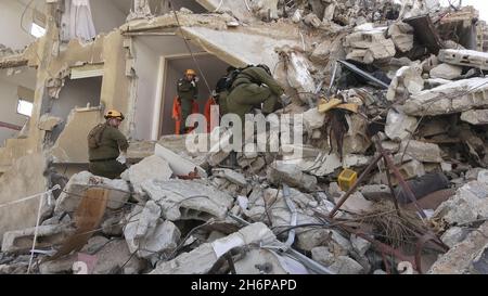 Israelische Soldaten der Rettungseinheit des Kommandos der Heimatfront gehen durch die Trümmer eines eingestürzten Gebäudes, während sie am 16. November 2021 in Tel Aviv, Israel, an einer Such- und Rettungsübung an einem großen Abrissplatz teilnehmen. Die Home Front-Übung simulierte Such- und Rettungsaktionen, die sich auf Szenarien vorbereiten, die Gebäude zerstören und Bürger aufgrund eines schweren Erdbebens oder massiver Raketeneinschläge einfangen könnten. Stockfoto