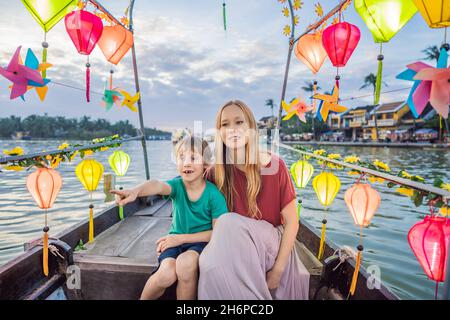 Glückliche Familie Mutter und Sohn von Reisenden reiten auf einem Nationalboot auf dem Hintergrund der alten Stadt Hoi, Vietnam. Vietnam öffnet sich danach wieder für Touristen Stockfoto