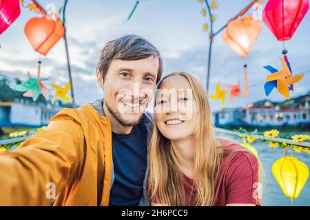 Ein glückliches Paar von Reisenden fährt auf einem Nationalboot auf dem Hintergrund der alten Stadt Hoi in Vietnam. Vietnam öffnet sich nach der Quarantäne wieder für Touristen Stockfoto