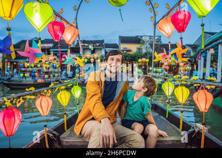 Glückliche Familie Vater und Sohn von Reisenden fahren ein nationales Boot auf dem Hintergrund von Hoi an alten Stadt, Vietnam. Vietnam öffnet sich danach wieder für Touristen Stockfoto