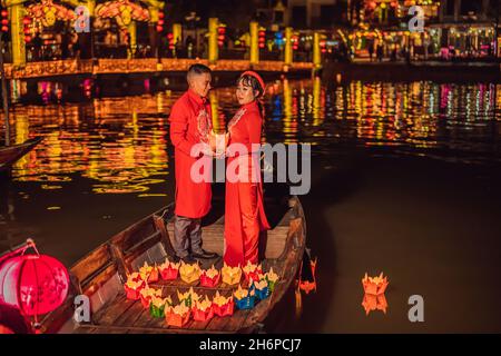 Hoi an, Vietnam, 27.12.2020: Glückliche Paare fahren auf einem Nationalboot auf dem Hintergrund der alten Stadt Hoi, Vietnam. Vietnam öffnet sich für Touristen Stockfoto