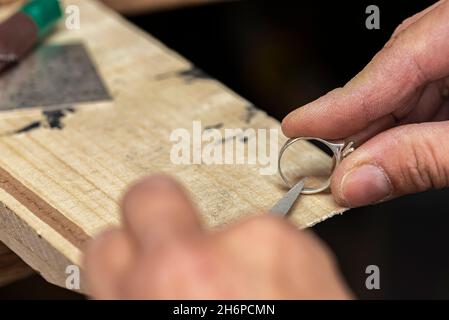 Reinigung der Innenseite des Silberrings mit einer Nadelfeile Stockfoto