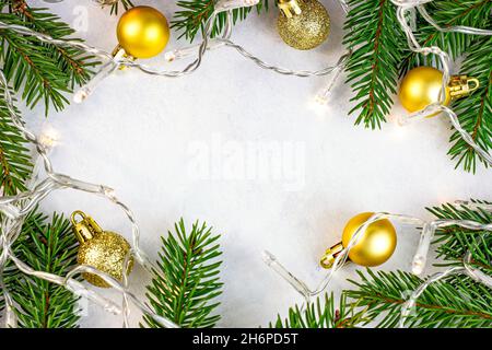 Grüne Tannenzweige, goldene Kugeln und Lichter als Weihnachtsdekoration auf weißem Hintergrund für Grußkarten mit Kopierfläche. Traditionelles Ch Stockfoto