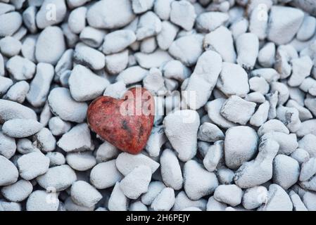 Ein geschnitztes / geformtes Herz aus einem Stück Granitstein auf einem Hintergrund aus weißen Felsen. Liebe, Romantik, Romantik Stockfoto