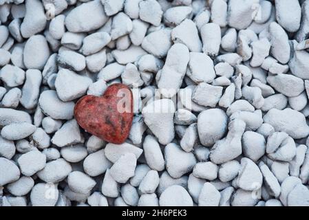 Ein geschnitztes / geformtes Herz aus einem Stück Granitstein auf einem Hintergrund aus weißen Felsen. Liebe, Romantik, Romantik Stockfoto