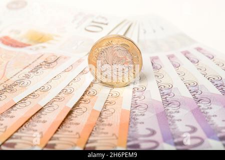 Geld: Ein und zwei-Pfund-Münzen saßen auf zehn und zwanzig-Pfund-Scheinen. £1 £10 £20 Pfund Sterling Währung. Nahaufnahme, Hintergrund. Stockfoto