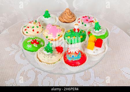 Ein Glasständer mit hausgemachten Kuchen, Cupcakes, Muffins im Weihnachtsstil dekoriert. Saisonale festliche Weihnachten Mini Dessert Cupcakes in traditionellen d Stockfoto