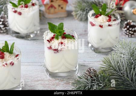 Weisser weihnachtlicher Mojito aus Likör, Tequila, Kokosmilch mit Granatapfelkernen, Kokosflocken und erfrischender Minze. Stockfoto