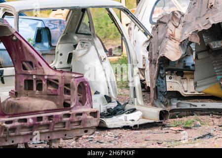 Metall zerbrochene Autos Körperteile im Freien aufgegeben. Autodumpe, Wrack auf einem Schrottplatz, bereit zum Recycling. Atmosphärischer, verwitterter Autoschrott Stockfoto
