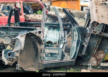 Verrostete Teile der Karosserie aus Metall wurden aufgegeben. Autodumpe, Wrack auf einem Schrottplatz, bereit zum Recycling. Atmosphärischer, verwitterter Autoschrott Stockfoto