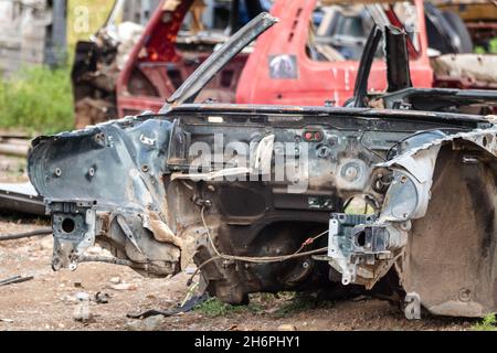 Verrostete Teile der Karosserie aus Metall wurden aufgegeben. Stimmungsvolle Nahaufnahme von verwittertem Auto-Junk. Autodumpe, Wrack auf einem Schrottplatz, bereit zum Recycling Stockfoto