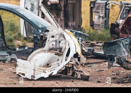 Metall abgerissen weißen Karosserie Teile im Freien aufgegeben. Autodumpe, Wrack auf einem Schrottplatz, bereit zum Recycling Stockfoto