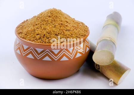 Gezackter Puder und Zuckerrohr isoliert auf weißem Hintergrund. Jaggery wird als Zutat in süßen und herzhaften Gerichten in der indischen Küche verwendet. Stockfoto