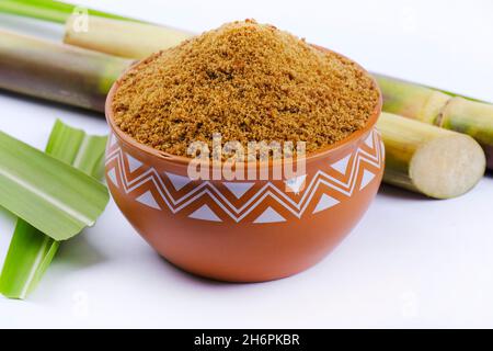 Gezackter Puder und Zuckerrohr isoliert auf weißem Hintergrund. Jaggery wird als Zutat in süßen und herzhaften Gerichten in der indischen Küche verwendet. Stockfoto