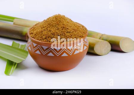 Gezackter Puder und Zuckerrohr isoliert auf weißem Hintergrund. Jaggery wird als Zutat in süßen und herzhaften Gerichten in der indischen Küche verwendet. Stockfoto