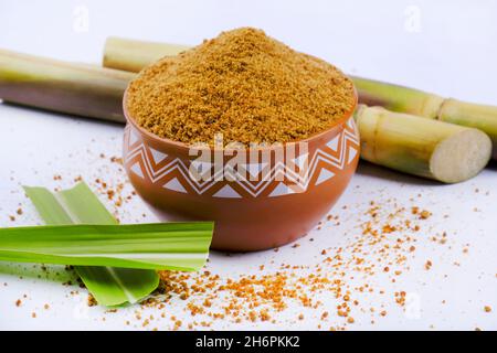 Gezackter Puder und Zuckerrohr isoliert auf weißem Hintergrund. Jaggery wird als Zutat in süßen und herzhaften Gerichten in der indischen Küche verwendet. Stockfoto