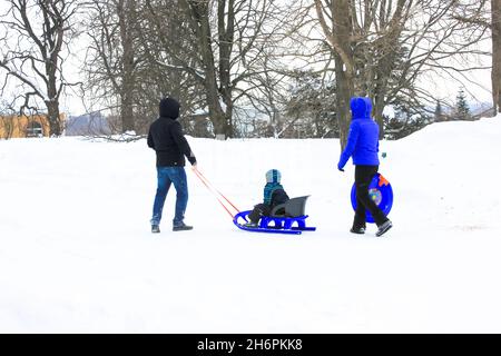 Kiew, Ukraine. 3. Januar 2021. Familie mit Kind im verschneiten Park. Schlitten im Winter. Stockfoto