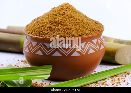 Gezackter Puder und Zuckerrohr isoliert auf weißem Hintergrund. Jaggery wird als Zutat in süßen und herzhaften Gerichten in der indischen Küche verwendet. Stockfoto