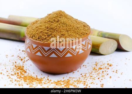 Gezackter Puder und Zuckerrohr isoliert auf weißem Hintergrund. Jaggery wird als Zutat in süßen und herzhaften Gerichten in der indischen Küche verwendet. Stockfoto