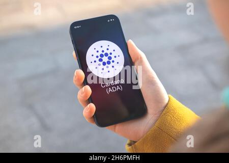 Cardano ADA Kryptowährungssymbol, Logo. Geschäfts- und Finanzkonzept. Hand mit Smartphone, Bildschirm mit Krypto-Symbol Nahaufnahme Stockfoto