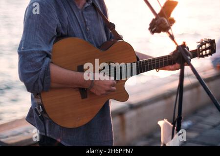 Nahaufnahme eines Straßenmusikers, der bei Sonnenuntergang klassische Gitarre spielt. Stockfoto