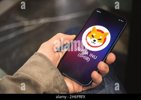 SHIBA INU Kryptowährungssymbol, Logo. Geschäfts- und Finanzkonzept. Hand mit Smartphone, Bildschirm mit Krypto-Symbol Nahaufnahme Stockfoto