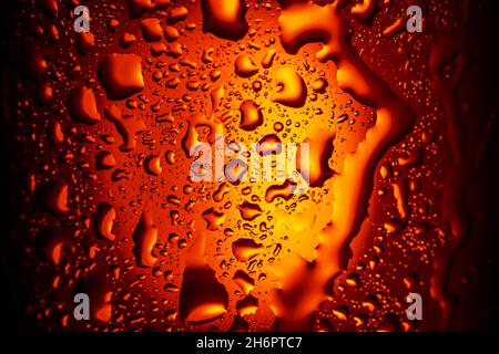 Hintergrund. Nahaufnahme. Tropfen auf ein Glas mit einem Orangengetränk. Bier, Tee Stockfoto