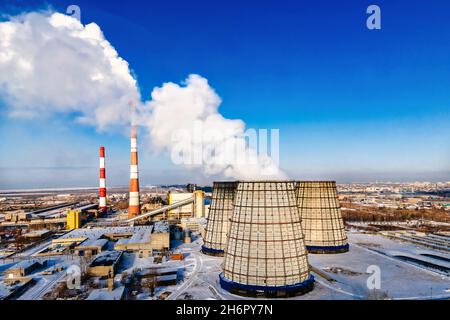 Rohre des thermischen Kraftwerks und Rauch gegen blauen Himmel. Draufsicht. Beginn der Heizsaison im Winter. Hintergrund. Stockfoto