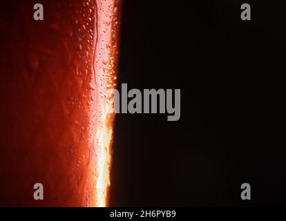Hintergrund. Nahaufnahme. Tropfen auf ein Glas mit einem Orangengetränk. Bier, Tee. Mit Nahaufnahme Stockfoto