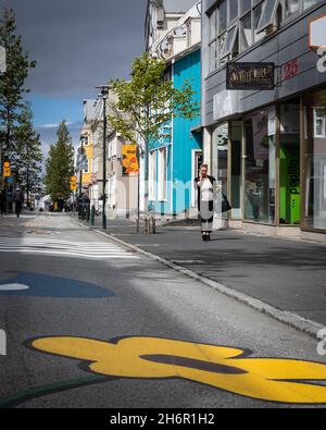 Reykjavik, Island - Juni 12 2021: Farbenfrohe Häuser in der Laugavegur Street in der Innenstadt von Reykjavik. Die Leute gehen die Straße entlang. Stockfoto