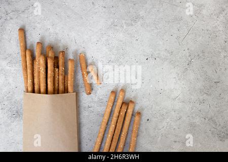 Brotstäbchen, mit Sesamsamen und Vollkornmehl auf grauem Hintergrund. Draufsicht, Kopierbereich. Stockfoto