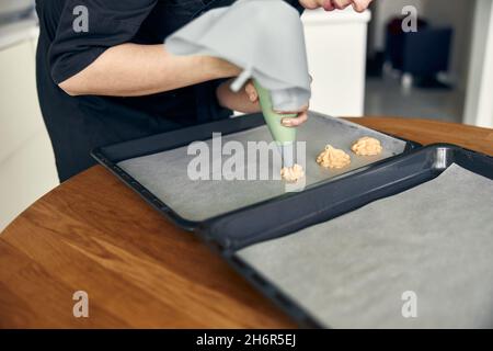 Schöne kaukasische Dame Köchin macht ecllairs mit Hilfe von Gebäck Gehäuse zu Hause Stockfoto