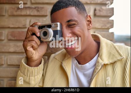 Lächelnder junger männlicher Fotograf, der sich gut und zufrieden fühlt Stockfoto