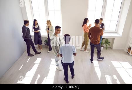 Aufnahmen verschiedener Personen, die im Büro stehen und in Gruppen über etwas diskutieren Stockfoto
