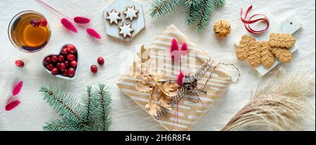 Winter Urlaub Hintergrund. Geschenkschachtel in braunem Papier verpackt. Natürliche trockene Eiche und Hase Schwanz Gras Dekorationen. Tannenzweige, Preiselbeere, Stern Stockfoto