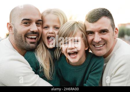 LGBT-Familie im Freien - Glückliche schwule Männer Paar und Söhne, die gemeinsam im Stadtpark Spaß haben - Fokus auf Center-Kindergesicht Stockfoto