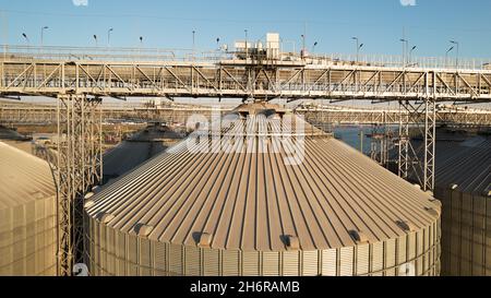 Getreideterminals des modernen Handelshafens. Silos zur Lagerung von Getreide in Strahlen untergehenden Sonnenlichtes, Draufsicht vom Quadcopter. Industrieller Hintergrund. Logist Stockfoto