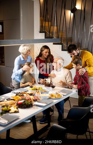 Glückliche Familie feiert Großvater Geburtstag mit Kuchen und Kerzen zu Hause Stockfoto