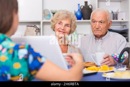 Junge Frau, die einem älteren Paar etwas auf dem Laptop zeigt Stockfoto