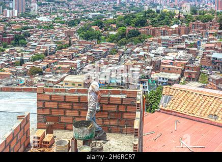Maurer bei der Arbeit auf einem Haus mit Blick auf die Stadt, Comuna 13, Medellin, Kolumbien. Stockfoto