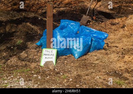 Ein Haufen Mist neben Ställen. Der Pferdebesitzer hat Mist eingesackt, um sie an lokale Gärtner zu verschenken. Stockfoto