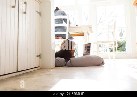 Acht Jahre alter Junge, der auf Kissen liegt, sich an den Händen kinn, einen Laptop-Bildschirm ansieht, Hausaufgaben macht. Stockfoto