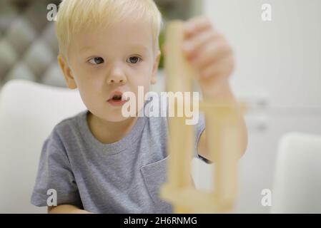 Kleiner Junge haben Spaß spielen Jenga zusammen - Brettspiel zu entfernen Holzblöcke und Kinder Freizeitkonzept. Stockfoto