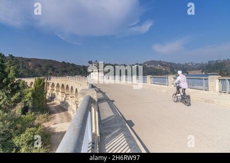 Los Angeles, CA, USA - 17. November 2021: Ein Radfahrer fährt über den Lake Hollywood über den Mulholland-Staudamm in Los Angeles, CA. Stockfoto