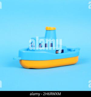 Kleines Plastikspielzeug-Schiff auf dem blauen Hintergrund Stockfoto