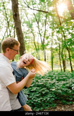 Beschnittene Ansicht eines Vaters und einer Tochter, die im Wald tanzen Stockfoto