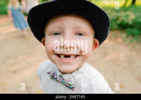 Nahaufnahme eines kleinen Jungen, der lächelt und zwei fehlende Vorderzähne hat Stockfoto